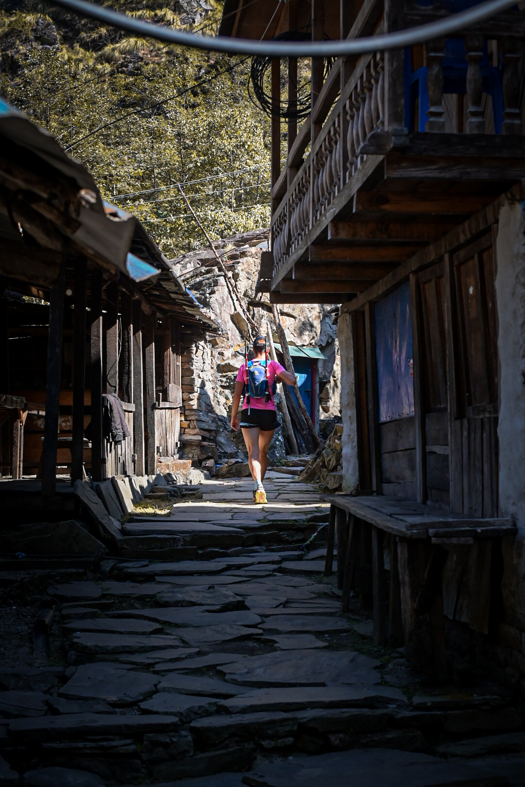 Runner in a pink top heading away up a flagstone village street