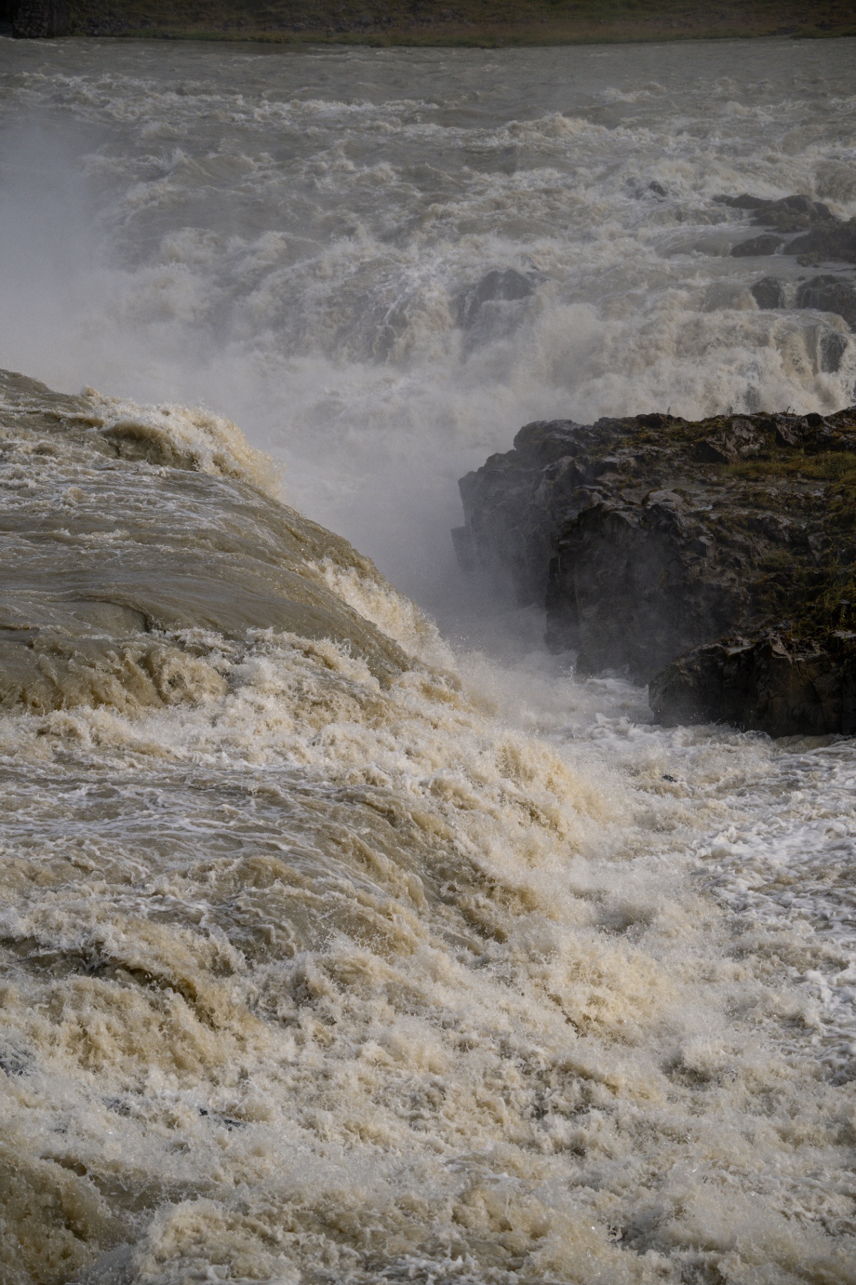 Glacial meltwater thundering over dark basalt rock in full flood