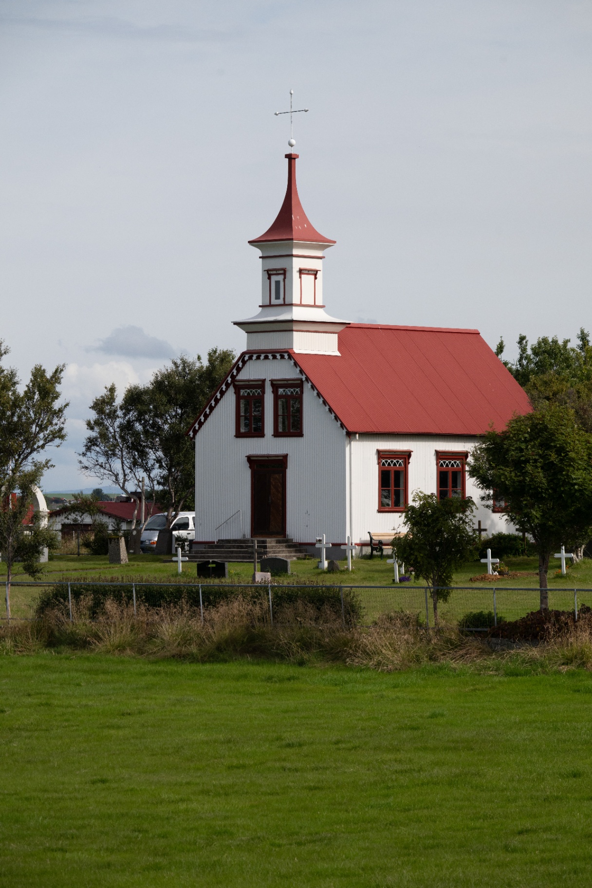Traditional white Icelandic church with a red roof beside its small churchyard