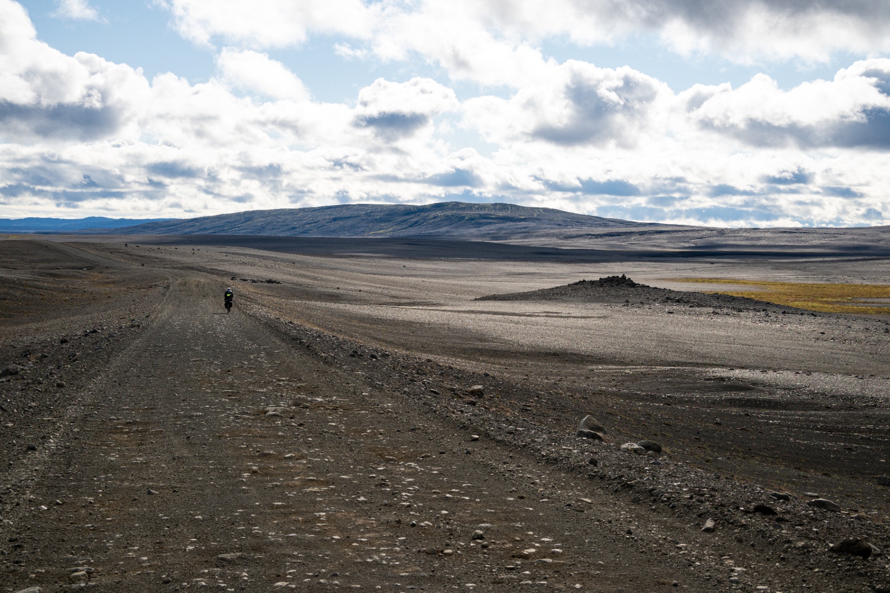 Lone rider dwarfed by a vast gravel track crossing Iceland's highland desert
