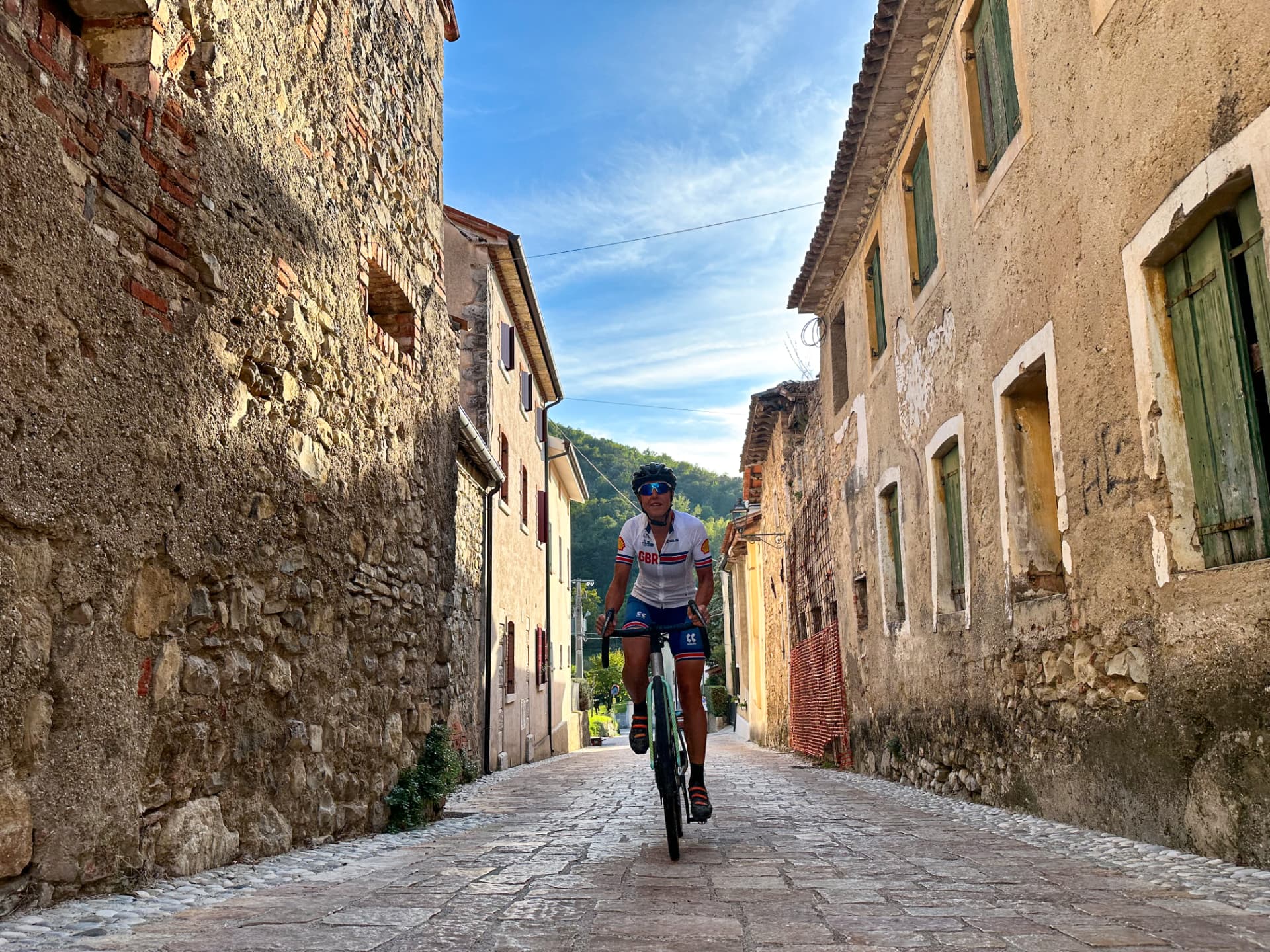 Rider in a GBR jersey climbing a cobbled street in an Italian village