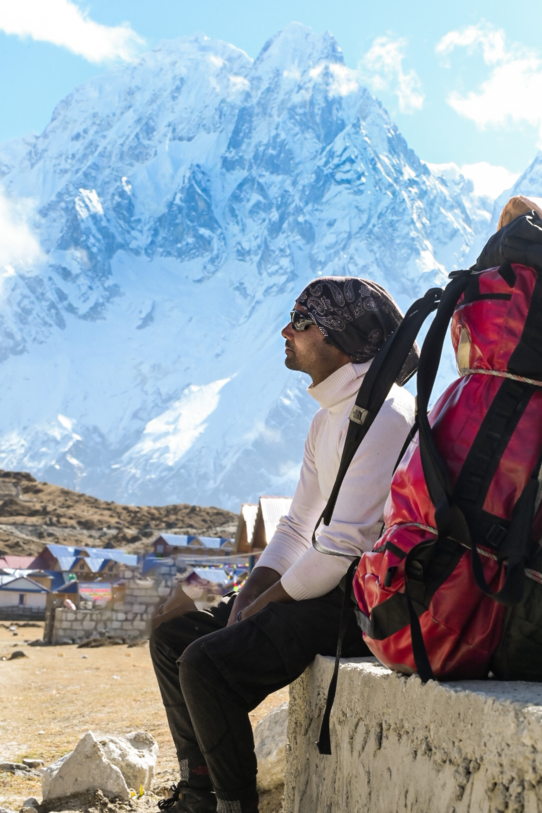 Trekker resting below a snow covered Himalayan peak