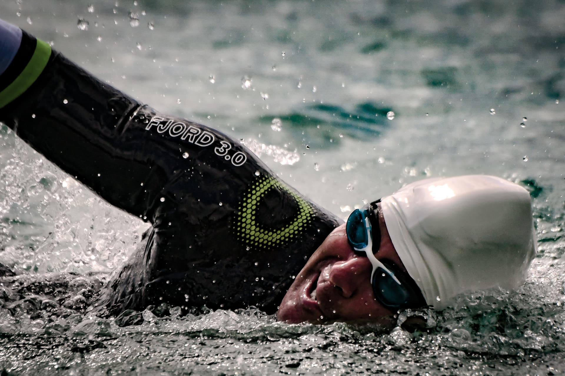 Open water swimmer mid stroke in a wetsuit, water spraying around the arm