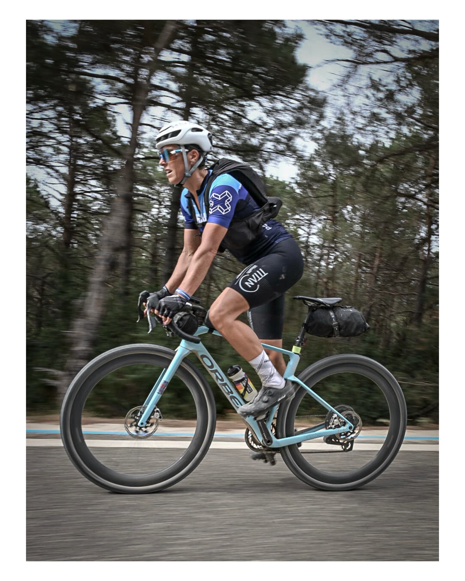 Panning shot of a cyclist at speed through pine forest with the background streaked by motion