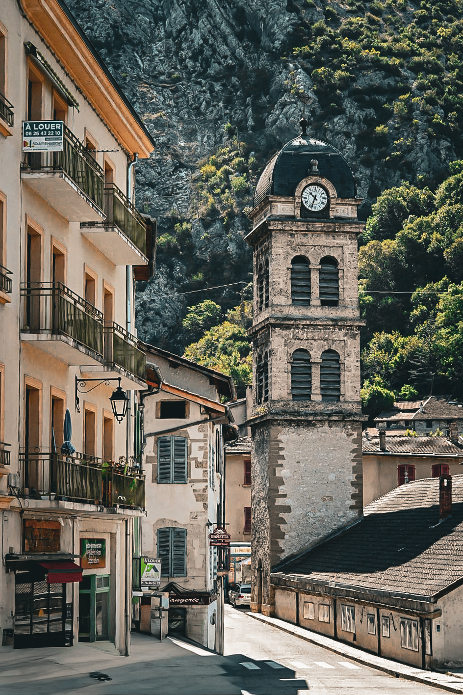 Alpine village clock tower beneath a steep rock face