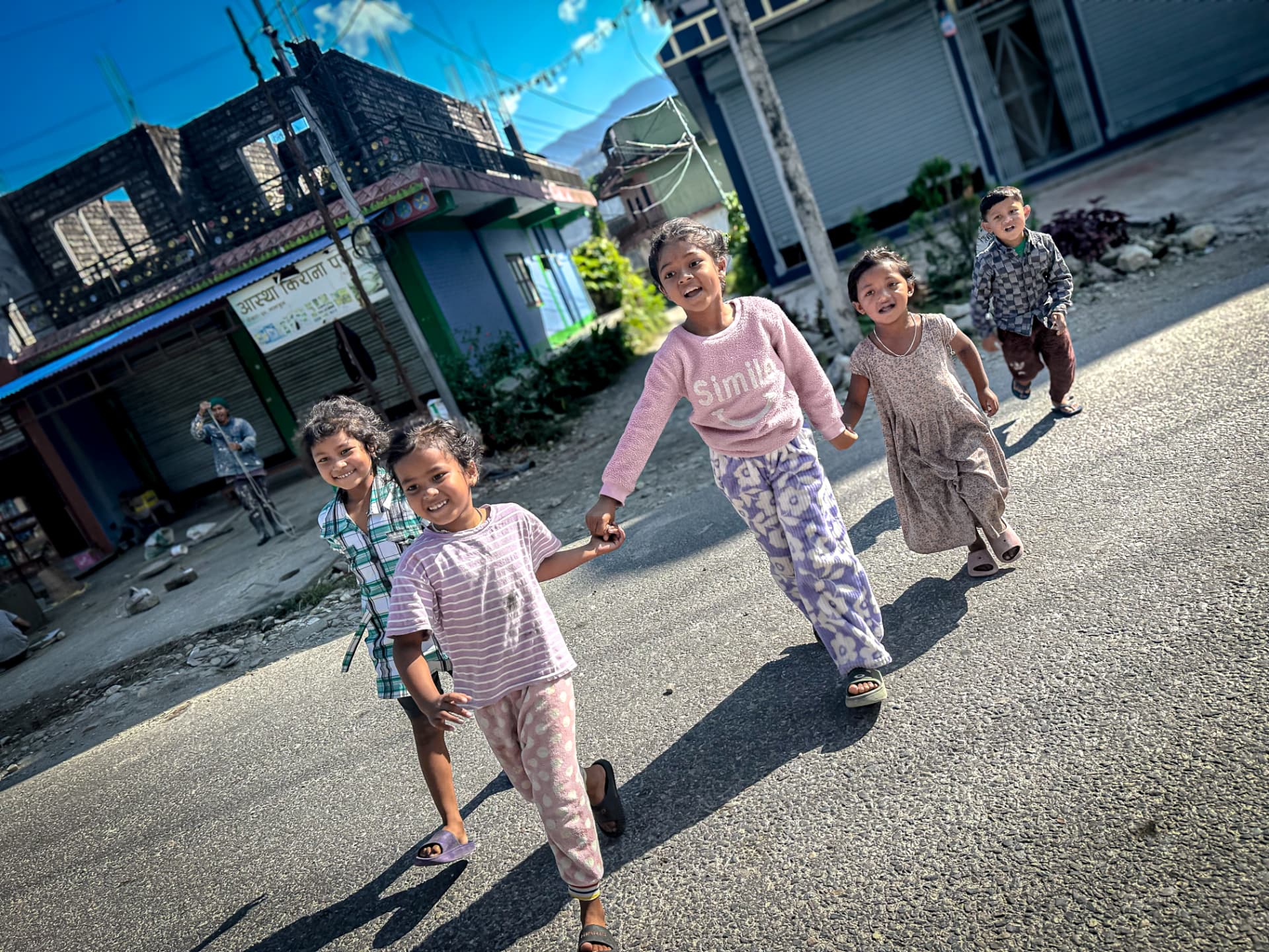 Children running hand in hand along a Himalayan village street