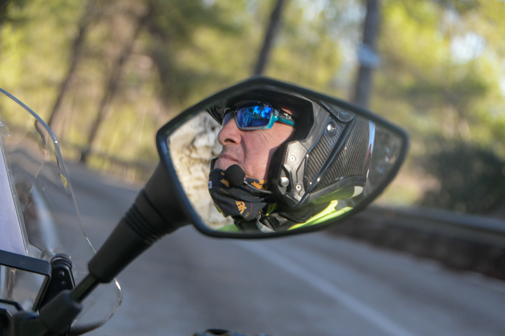 Motorbike outrider reflected in a wing mirror on a forest road