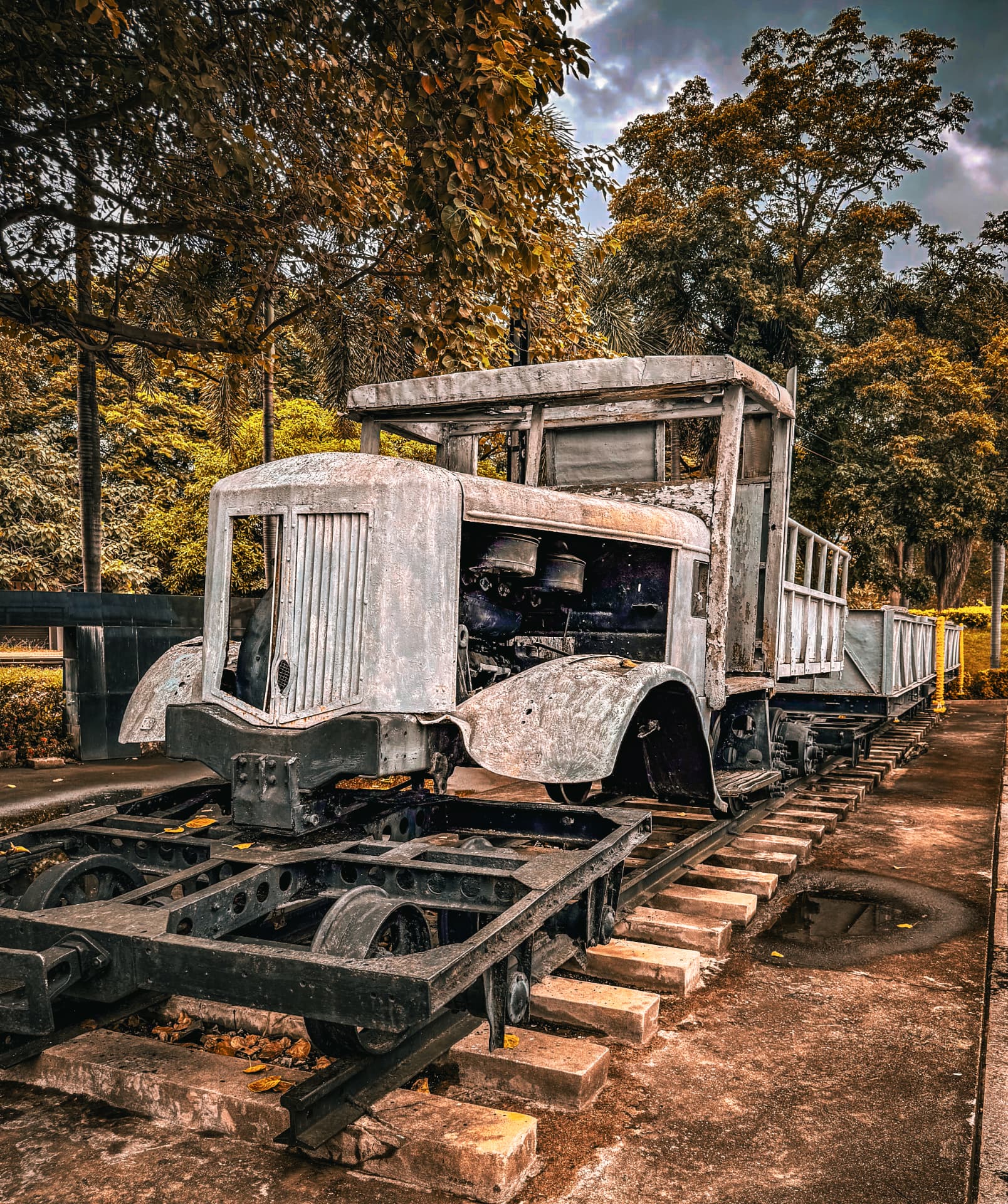 Weathered vintage railway truck on preserved tracks under golden trees