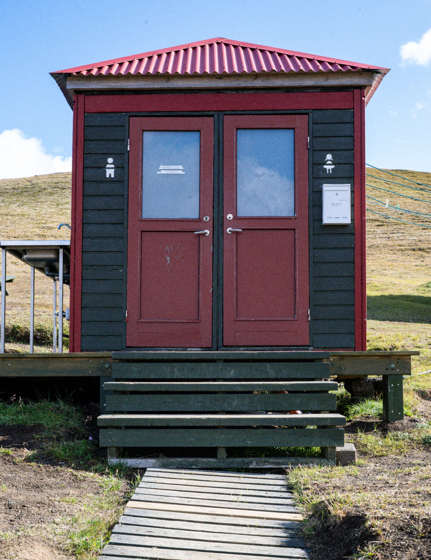 Red and black highland toilet block with a boardwalk leading up to it