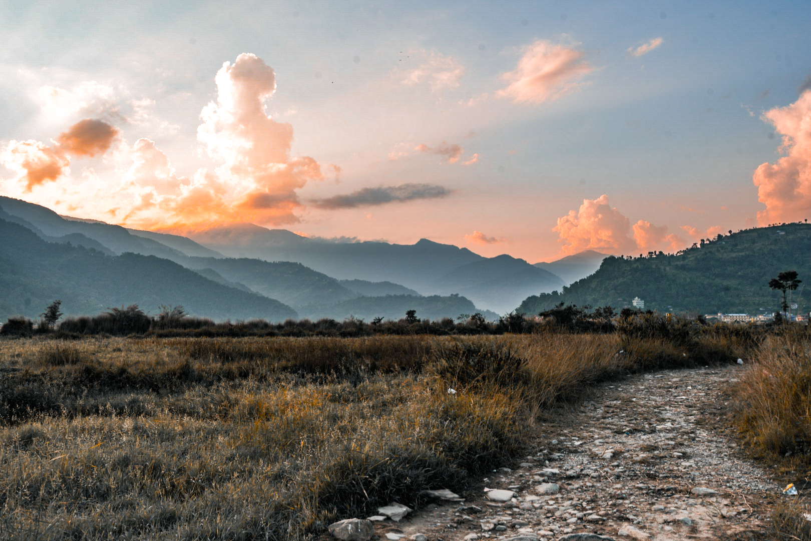 Sunset light on foothills above a gravel track and dry grassland