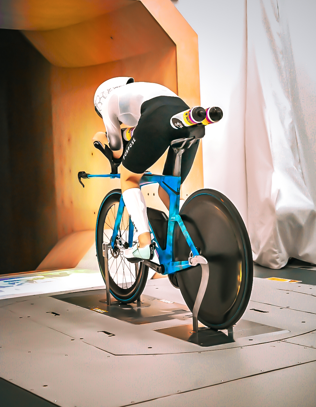 Cyclist in the wind tunnel on a blue time trial bike