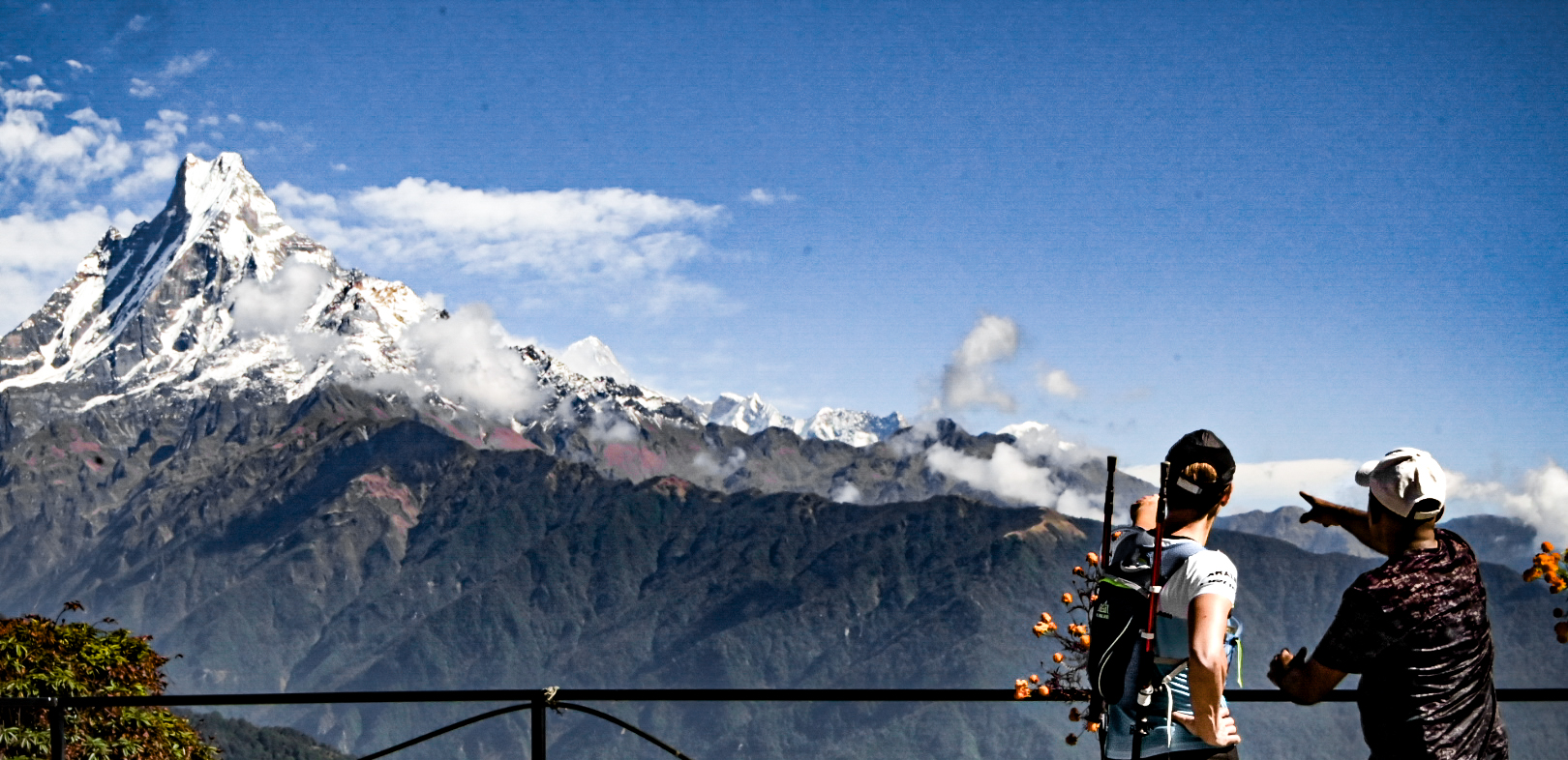 Two runners on a viewpoint pointing out the Annapurna skyline