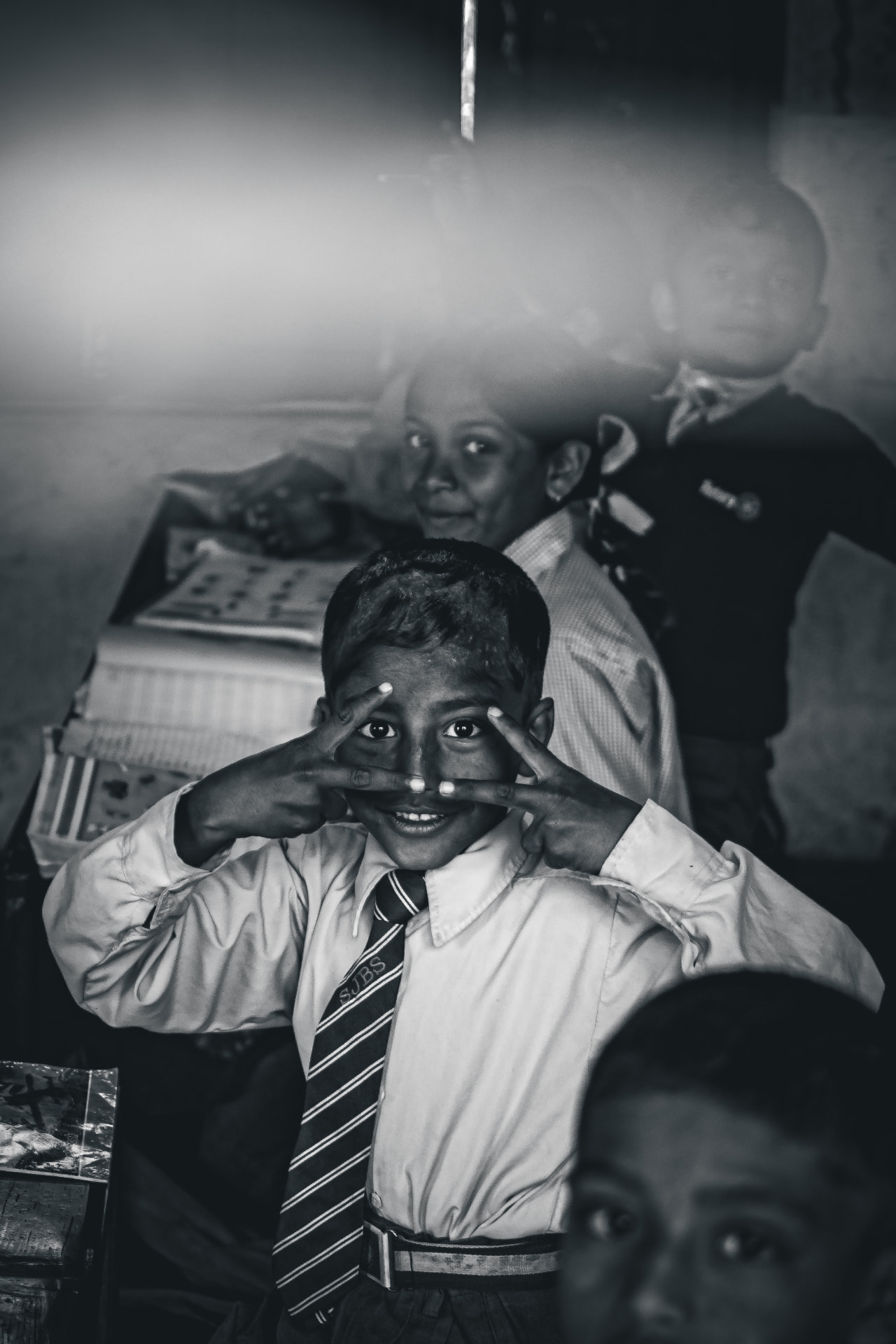 Black and white portrait of a schoolboy framing his eyes with his fingers