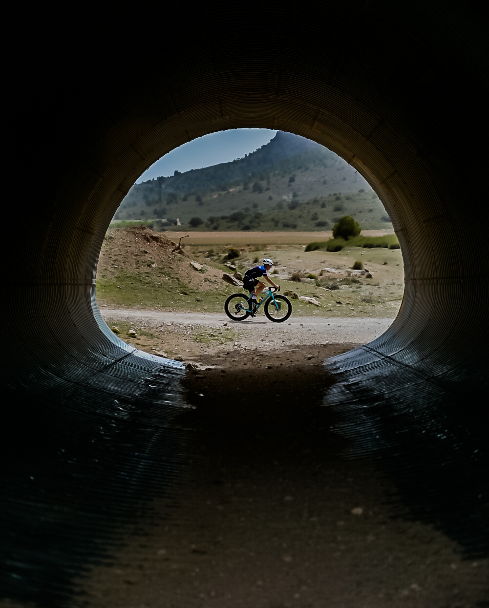 Cyclist framed through a dark road tunnel opening