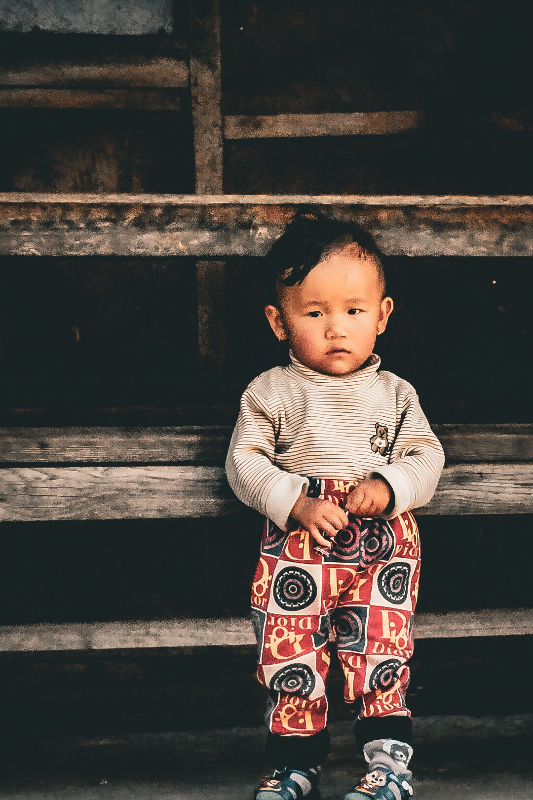 Documentary portrait of a young child on a wooden bench in warm evening light