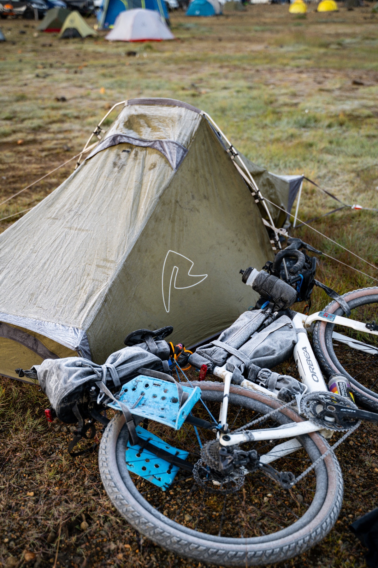 Frost covered bikepacking tent and loaded gravel bike at a highland campsite