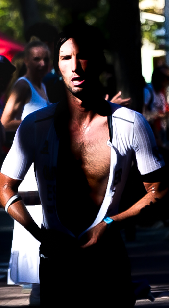 Triathlete opening his tri suit in harsh sunlight after the finish