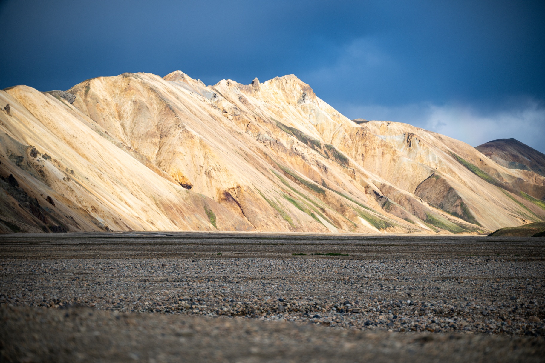 Sunlit rhyolite ridges of Landmannalaugar under a dark storm sky
