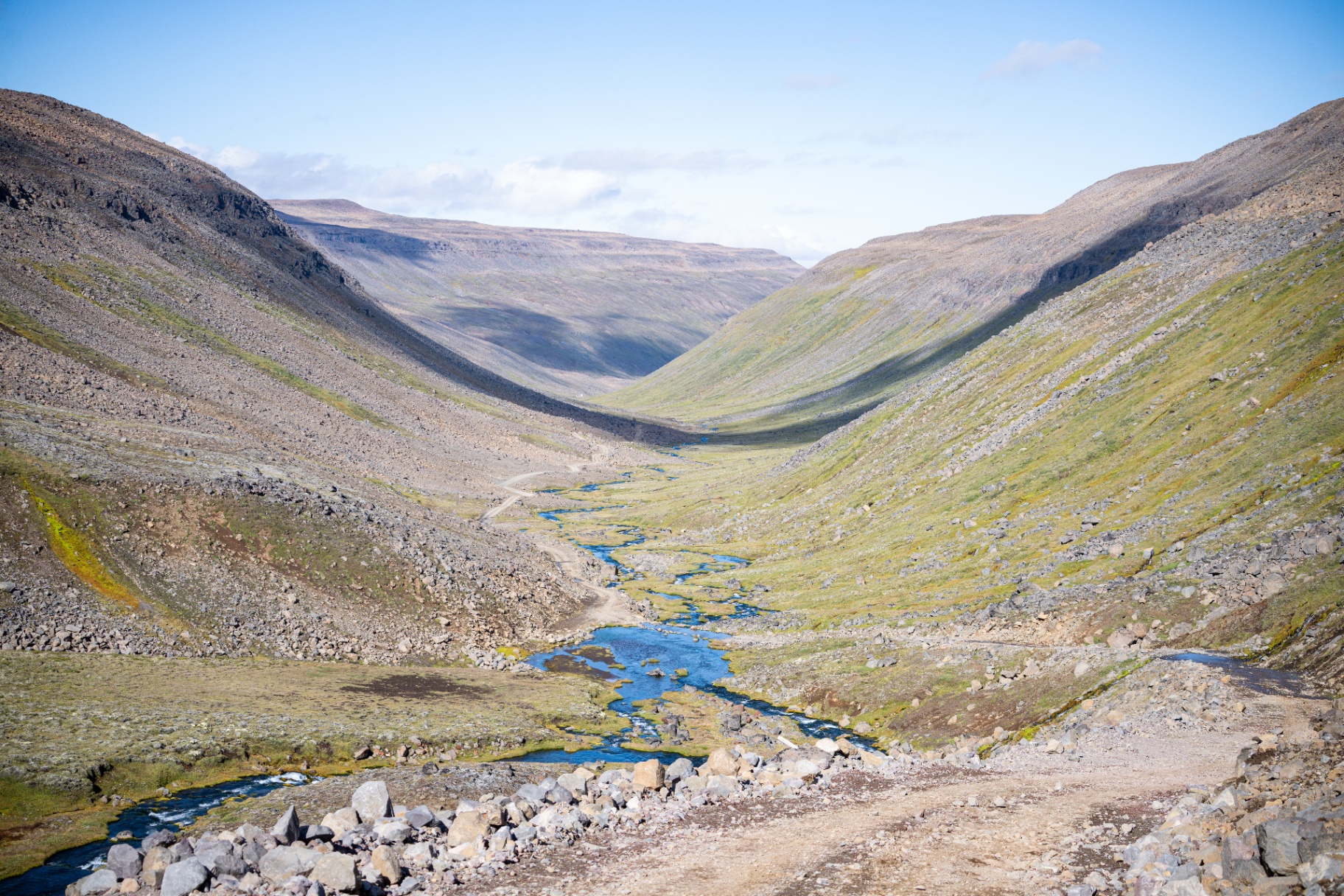 Glacial river threading a broad U shaped valley with a gravel track alongside