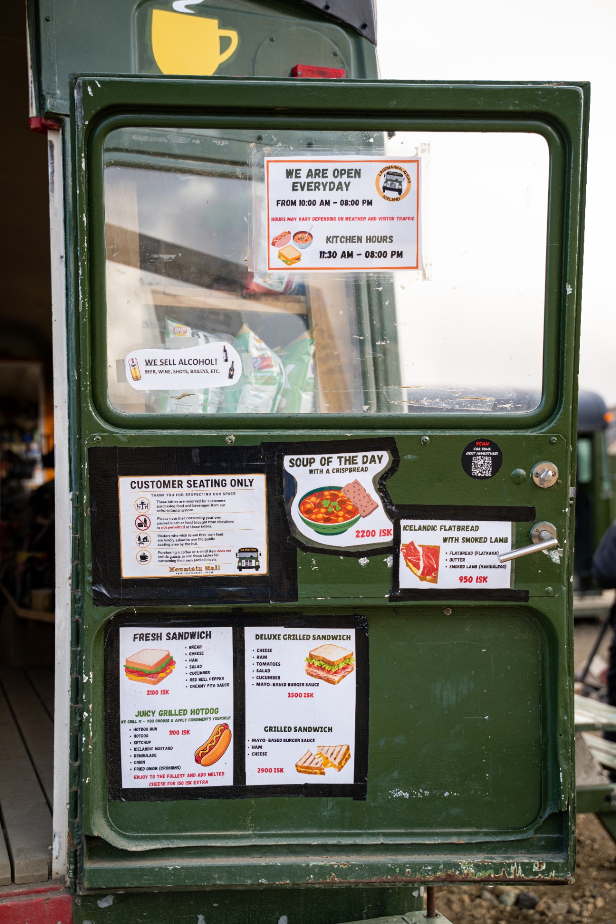 Green mountain hut cafe door covered in handwritten Icelandic menus