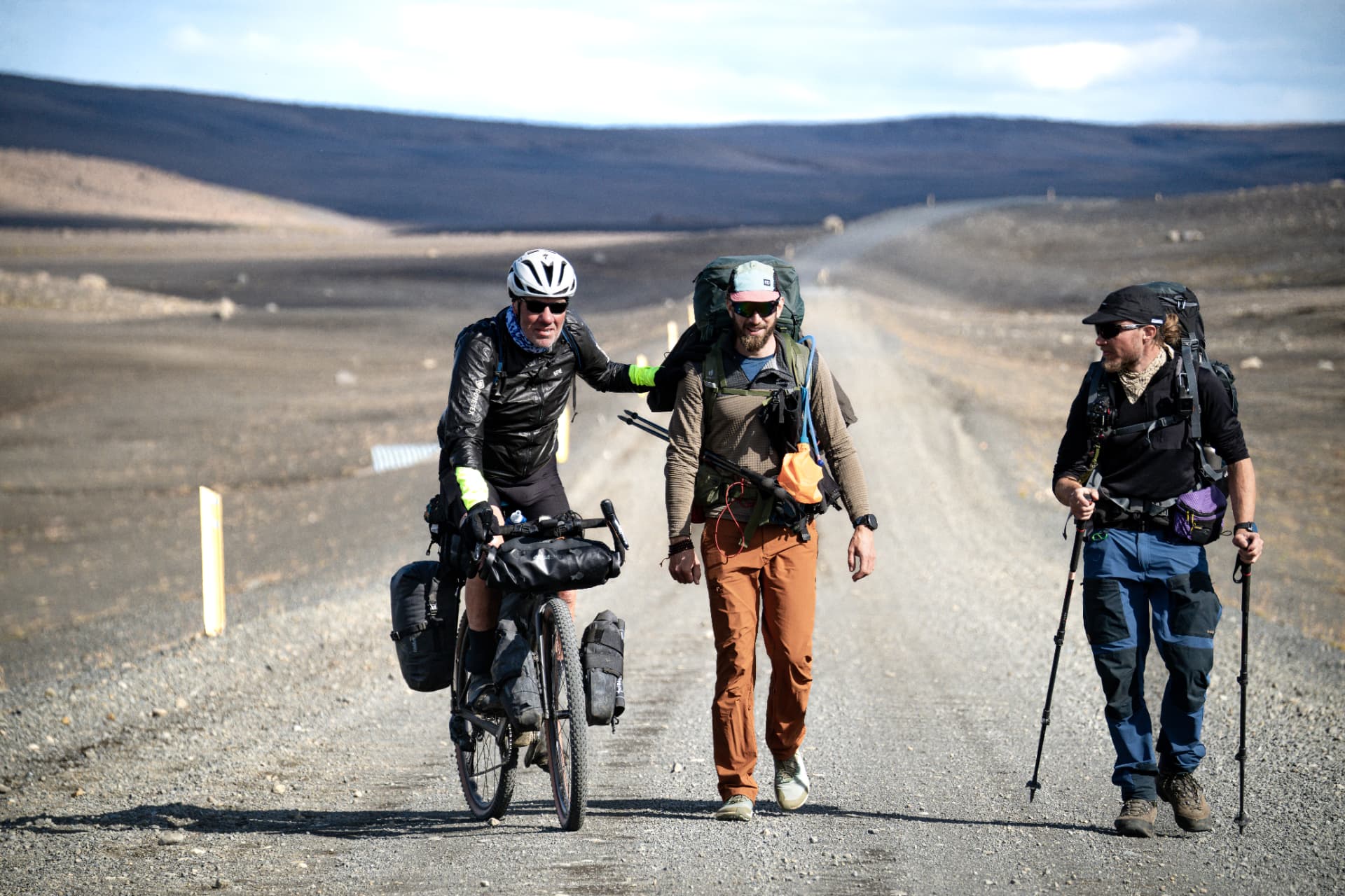 Three bikepackers and hikers sharing a gravel road through Iceland's volcanic interior