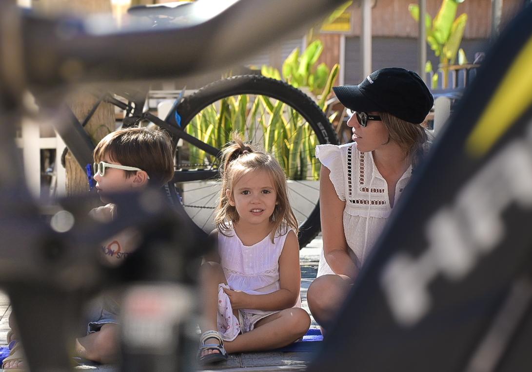 Family watching the race from the roadside, framed through bike wheels