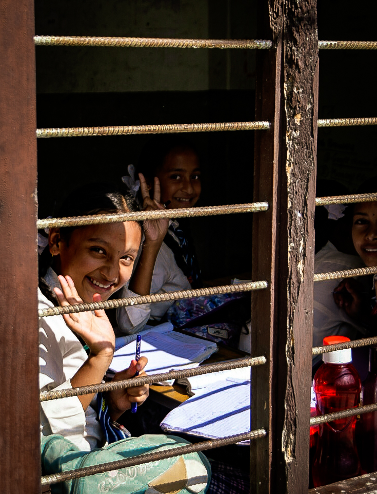 Schoolgirls waving through a barred classroom window